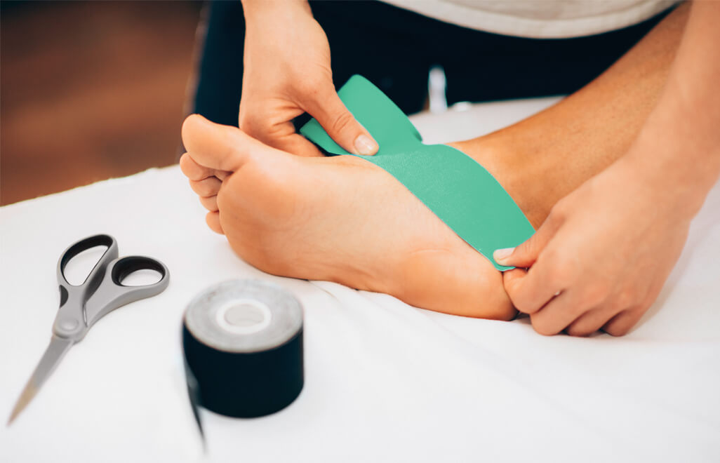 Village Physio & Sports Injury Clinic - Image of physiotherapist taping a clients foot.